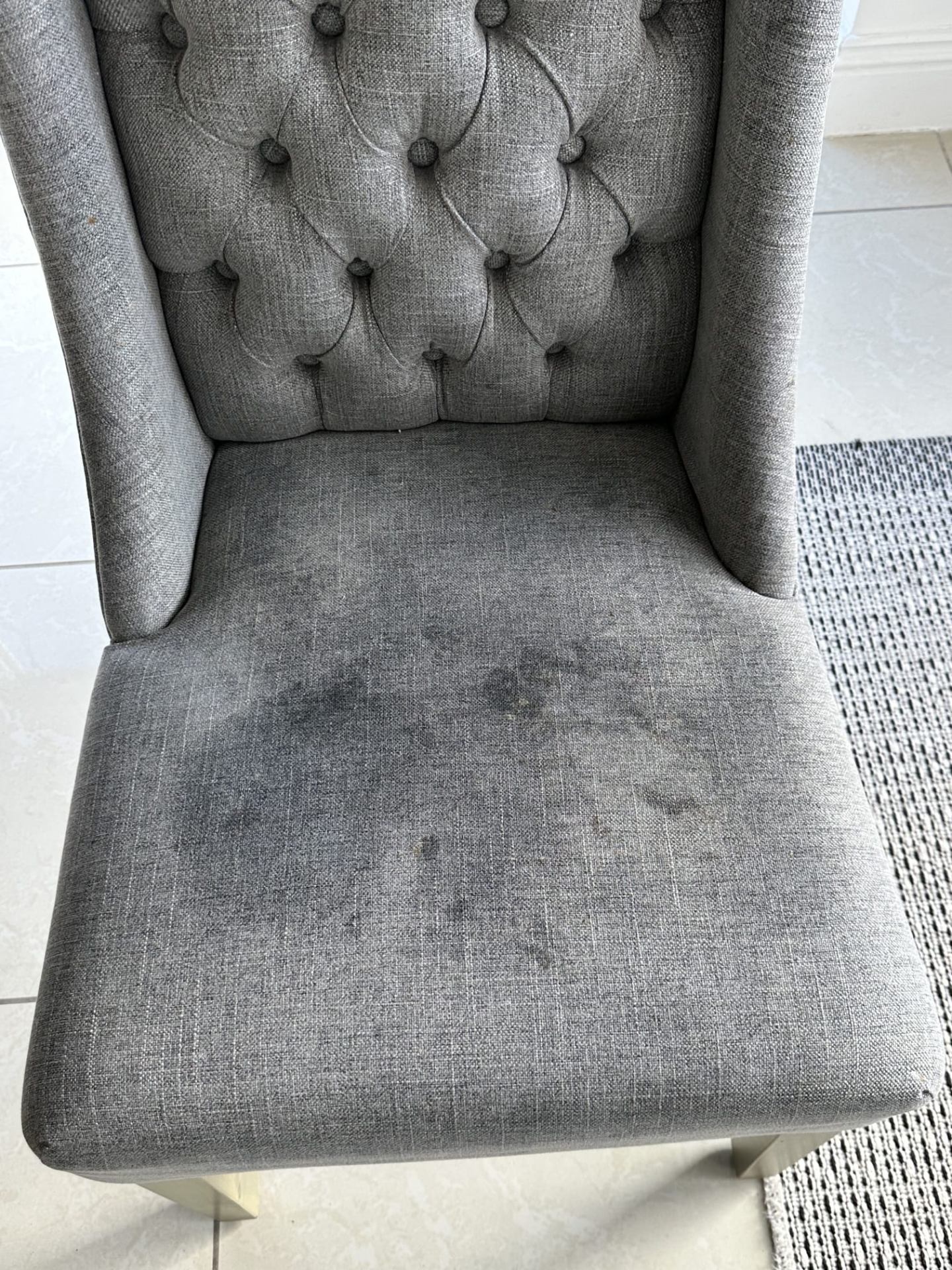 Grey tufted dining chair with stains before professional cleaning