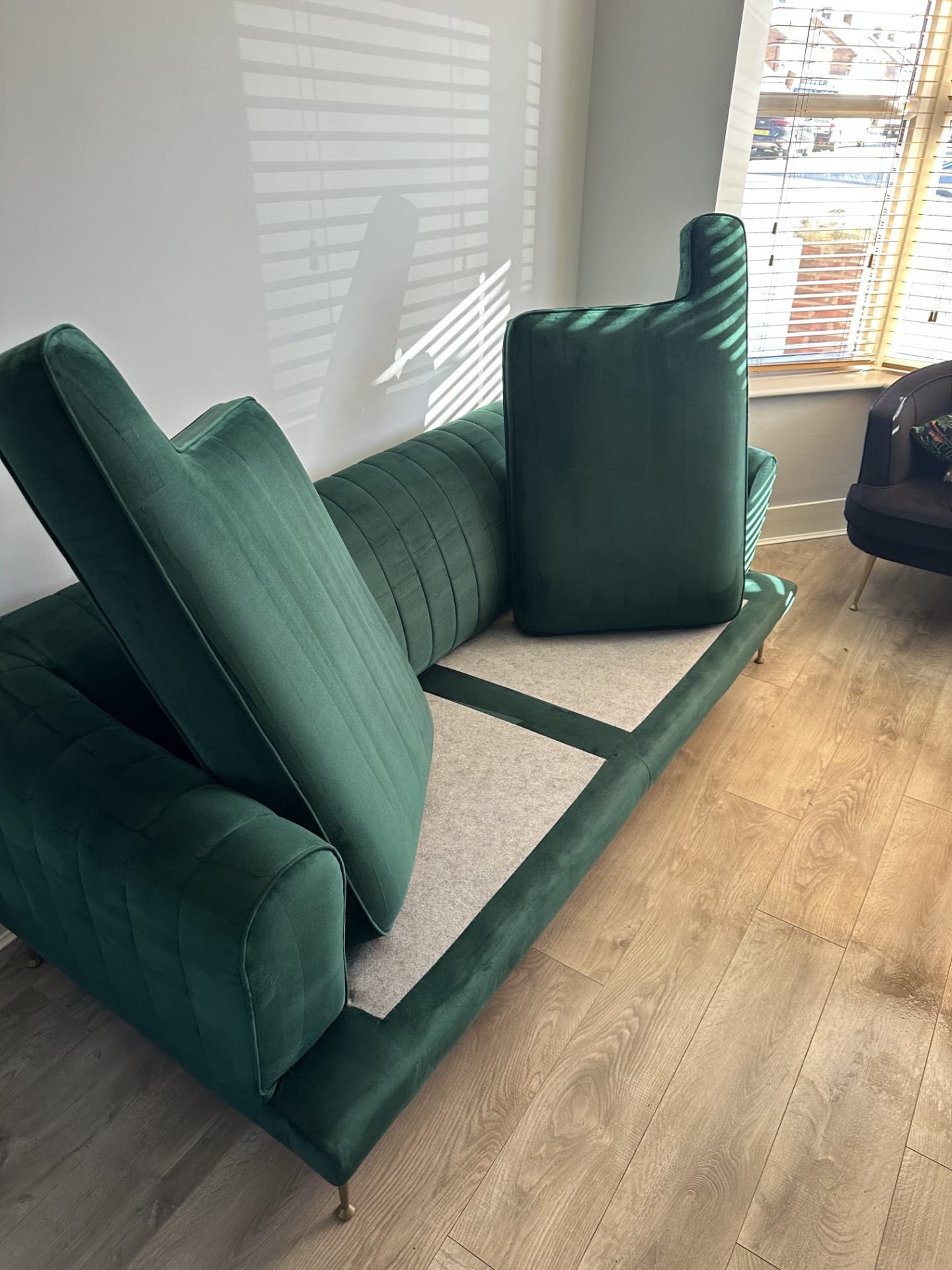 Green velvet sofa with cushions removed during professional cleaning