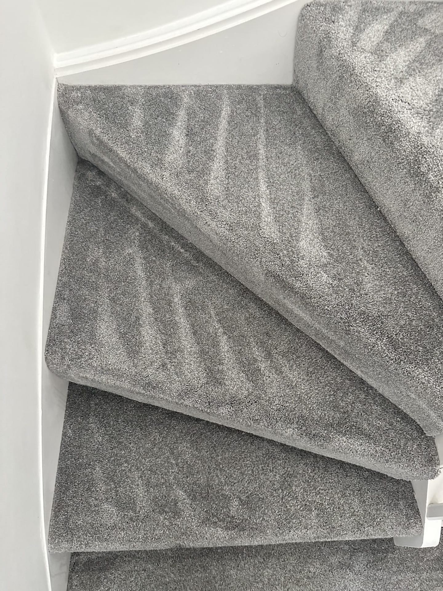 Grey carpet corner stairs professionally cleaned with visible before and after line