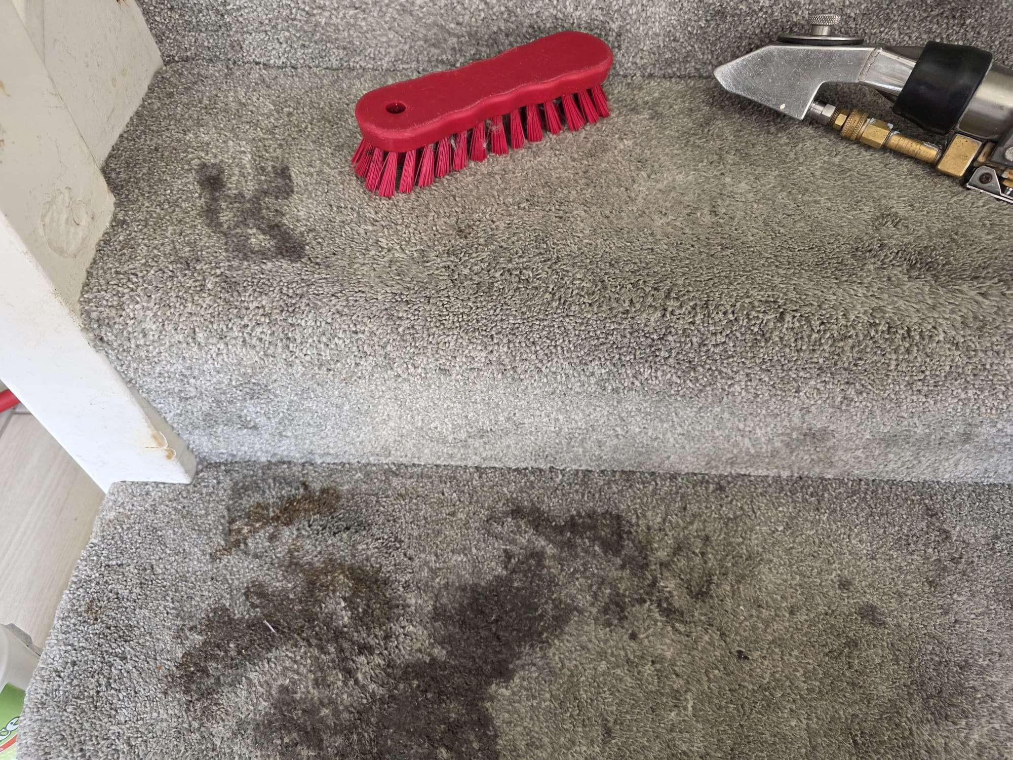 Stained grey carpet stairs with brush and extraction tools during cleaning